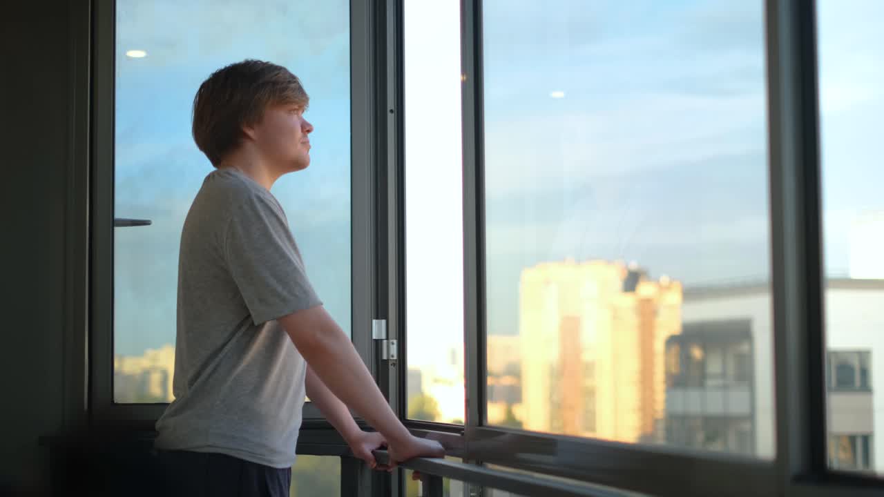 adolescente mirando por una ventana a una vista de la ciudad