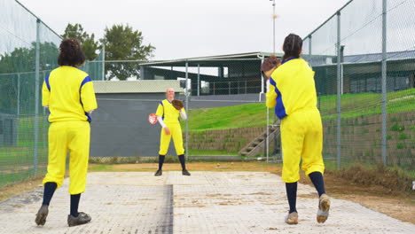 multiracial female baseball players catching and throwing the ball to each other on a pitch