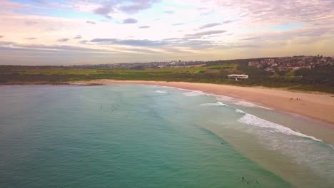 Toma-Aérea-De-Surfistas-Atrapando-Olas,-Surfeando-En-Invierno-En-Una-Mañana-Ventosa-Y-Nublada,-Maroubra-Beach,-Sydney,-Australia