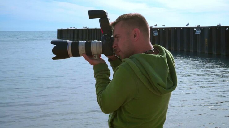 Photographer taking photo at sea beach. Close up of photographer with camera