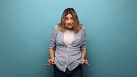 woman with wavy hair turning out empty pockets, worried about debts, no cash for living.
