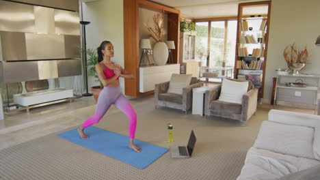 mujer de raza mixta practicando yoga en casa