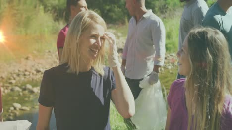 video of lights over diverse happy group picking up rubbish in countryside