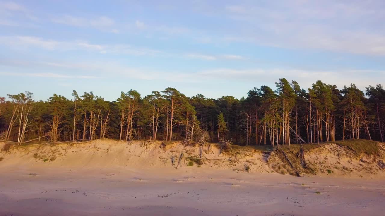 Wunderschöne einleitende Luftaufnahme der Ostseeküste an einem sonnigen Abend zur goldenen Stunde, mit weißem Sandstrand, Küstenerosion und Klimawandel, eine aufsteigende Weitwinkel-Drohnenaufnahme, die sich vorwärts bewegt.