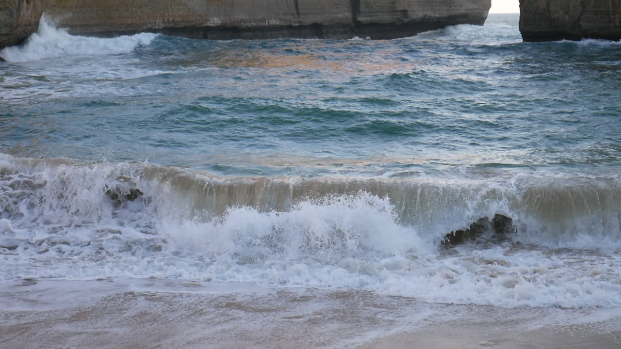 Beautiful turquoise ocean waves crashing on the sandy beach Loch Ard Gorge in Australia