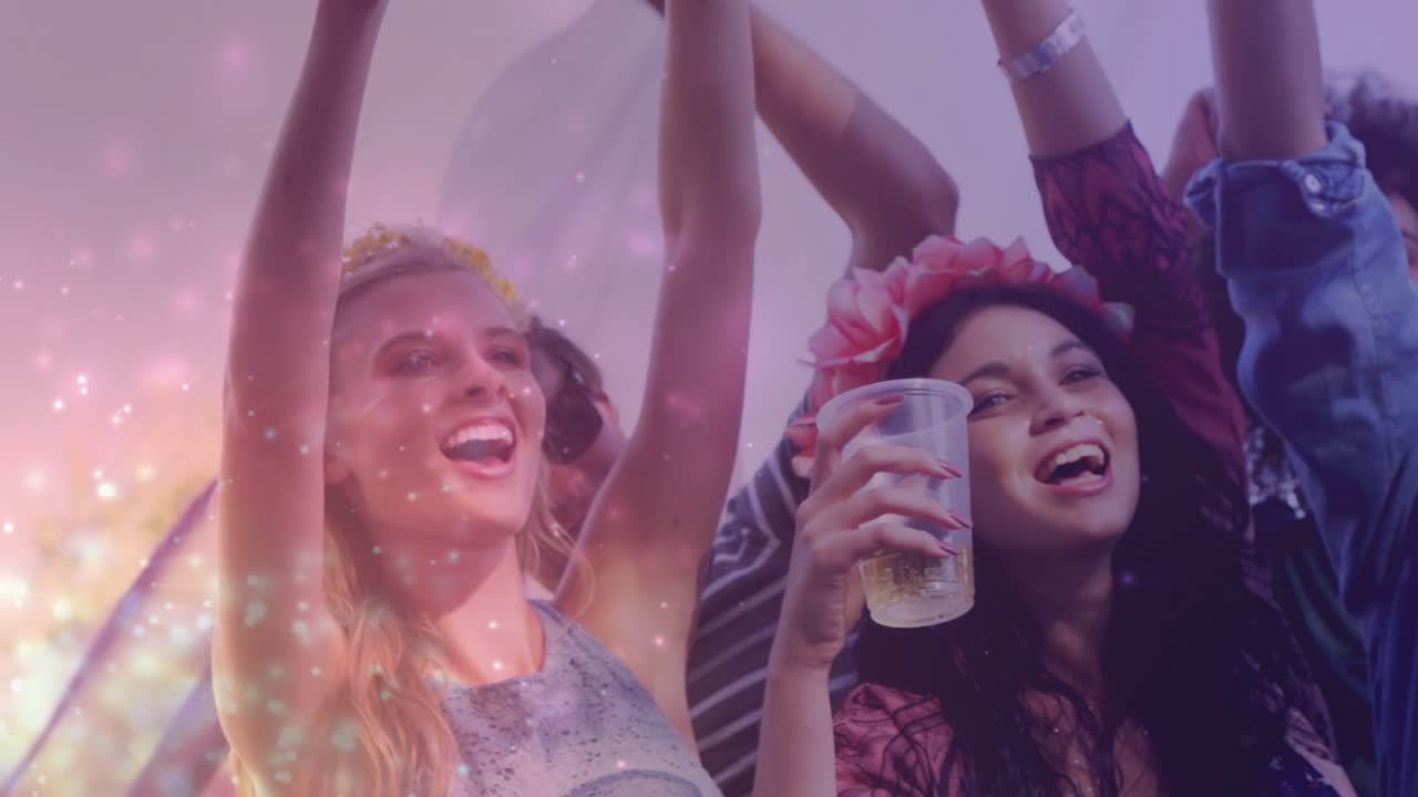 Front-row festival attendees raising cups and cheering after set, pink sparkle showing wristbands