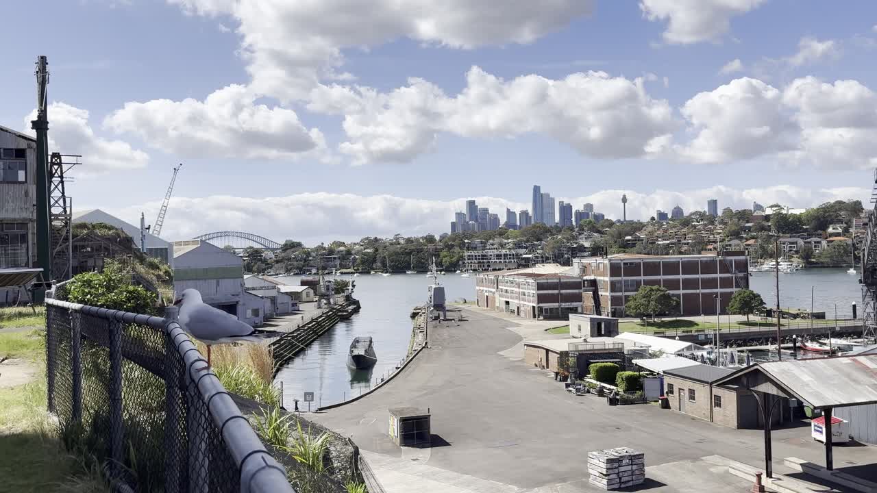 A seagull stands on a fence looking over the port area and the city from the historical industrial Cockatoo Island in Sydney harbour, Australia