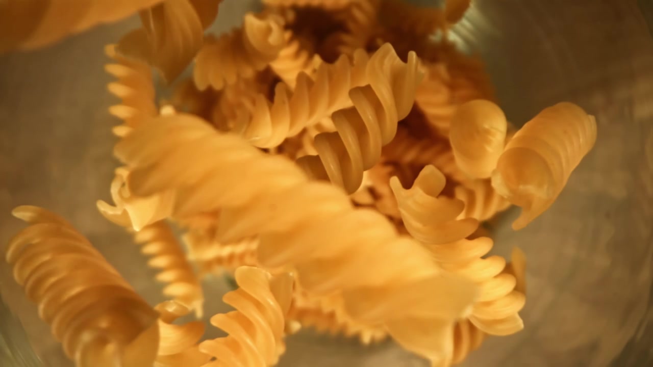 Slow Motion Uncooked Fusilli Pasta Falling into a Bowl