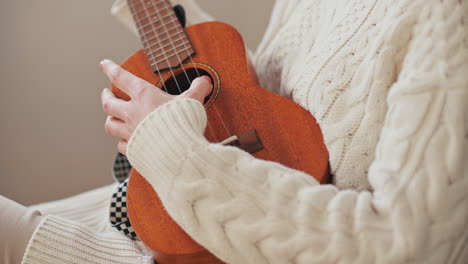 the hands of an unrecognizable girl playing the ukelele