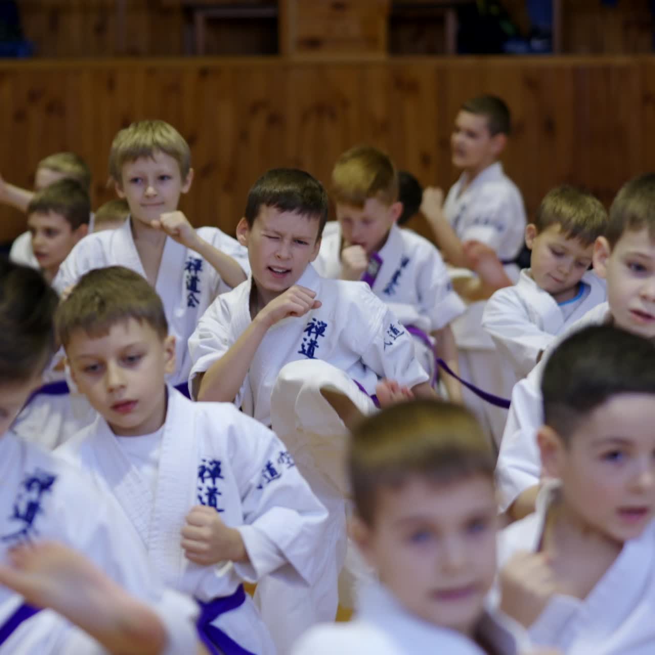 Working hard during karate training. Teenage boys in white kimonos practicing kicks. Blurred foreground