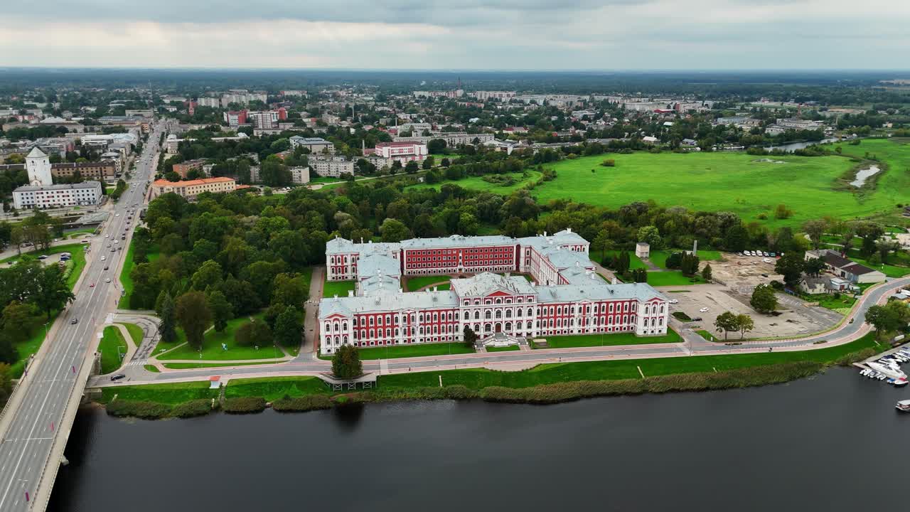 Jelgava Palace beside Lielupe River with Bridge connecting urban zones showing baroque architecture water flow and regional layout in Zemgale Region of central Latvia, Drone establishing shot