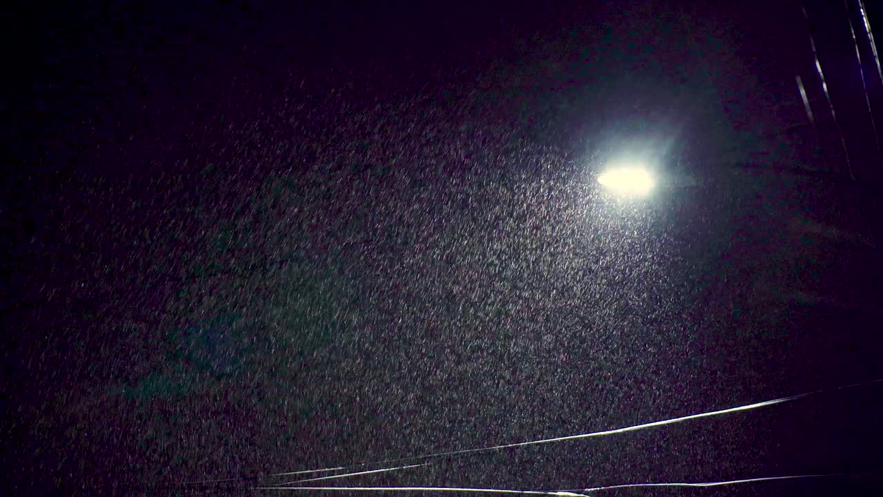 la luz de la calle durante la noche empujando a través de una fuerte lluvia de nieve