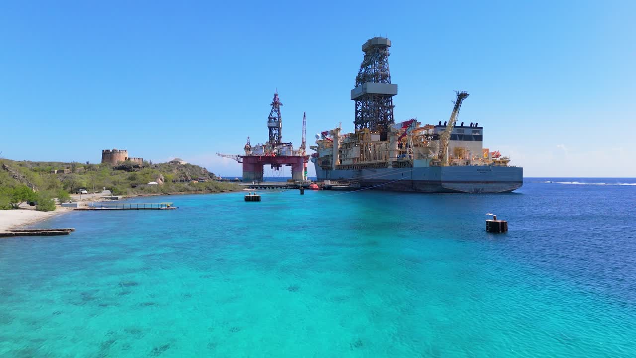 Aerial dolly to Noble Voyager oil rig platform in clear turquoise waters near Fort Beekenburg