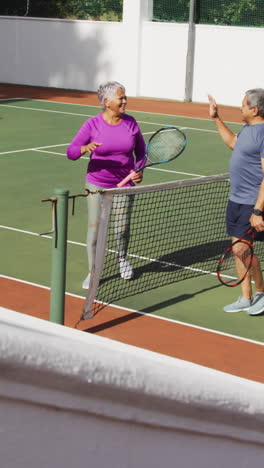 video of happy biracial senior couple clapping hands after match on tennis court