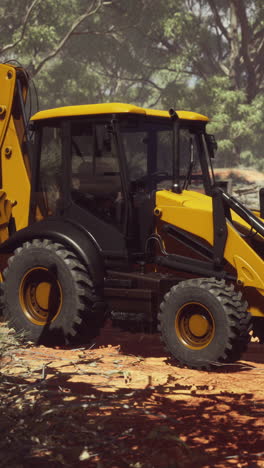 yellow excavator in a forest clearing