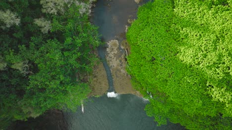 drone slowly tracking down birdseye view of waterfall and pool at opaekaa falls, hawaii