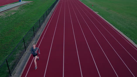 Jovencita-Pista-De-Atletismo-Corre-Hacia-Y-Bajo-La-Cámara-Aérea