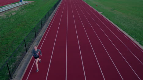 teen girl running track runs towards and under aerial camera