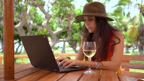 Young-woman-working-on-laptop,-remote-Work-,-digital-nomad,-happy-with-wine-outdoor-office