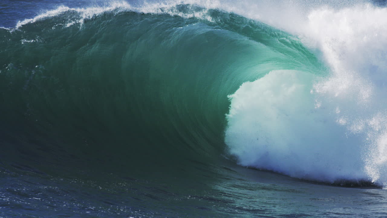 Curling wave glows in soft backlight, mist floating above deep water motion