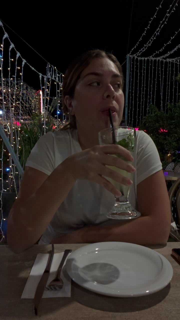 Ung kvinde drikker en Mojito-cocktail med et sugerør