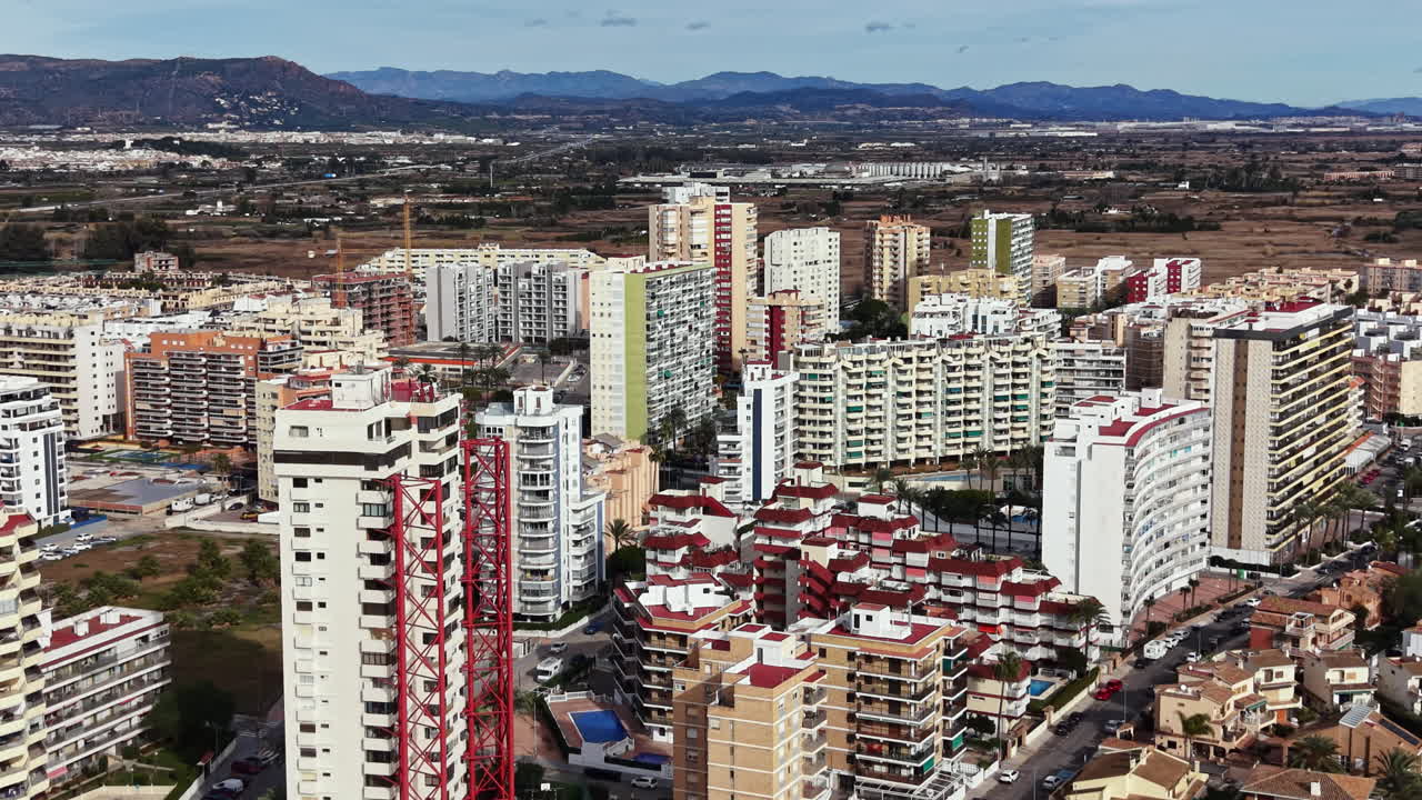 Vista de edifícios urbanos e arredores em uma cidade durante o dia, destacando áreas residenciais e comerciais perto de montanhas.