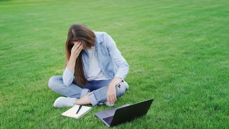 mujer reflexiva estudio en línea en el ordenador portátil en el parque de verano