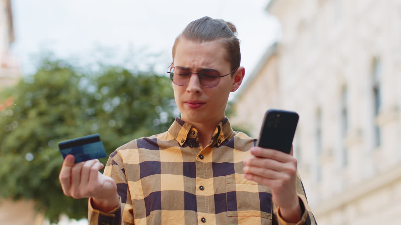 hombre conmocionado tratando de pagar compras en línea con teléfono inteligente tarjeta de crédito bloqueada falta de saldo de dinero