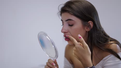 young woman using hand mirror for beauty routine