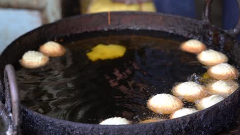 some nepali sweets frying in a kettle of oil