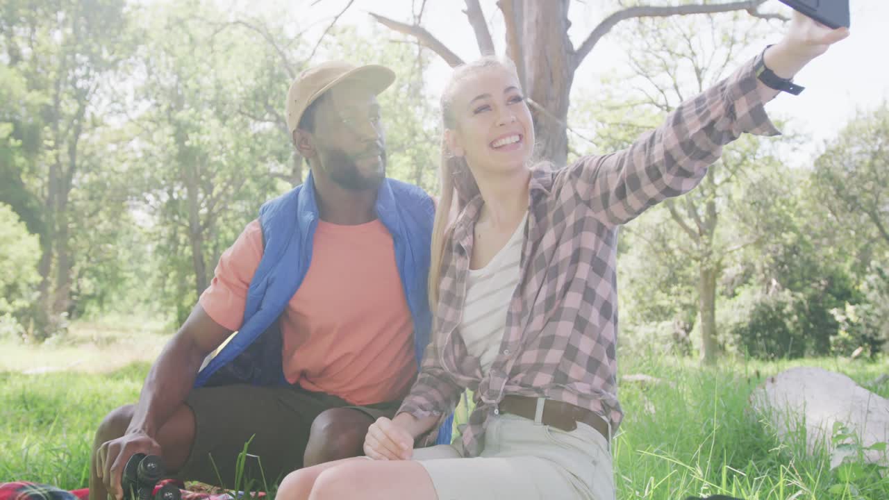 pareja feliz acampando y tomando selfies con teléfonos inteligentes en el parque, cámara lenta
