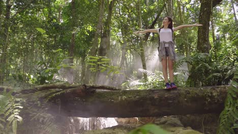 girl hiker enjoying on log in the forest, slow motion