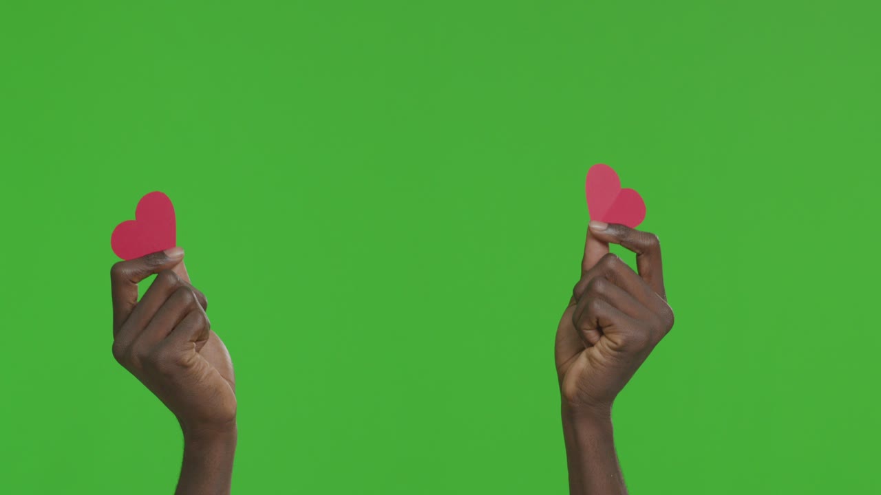 녹색 스크린에 종이 심장을 들고 있는 손