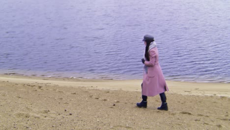 woman walking on the beach by a calm lake