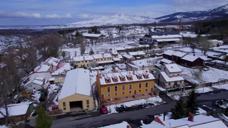 low level push in aerial over the town of pradera de navalhorno in spain to reveal the snow-covered mountains on the horizon