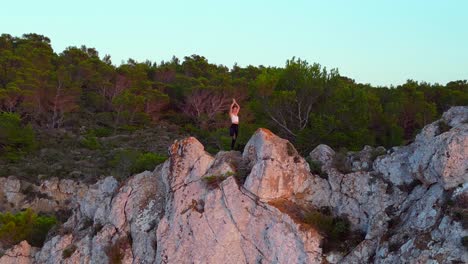 hermosa vista aérea de arriba vuelo ibiza acantilado yoga árbol pose modelo chica puesta de sol por la noche