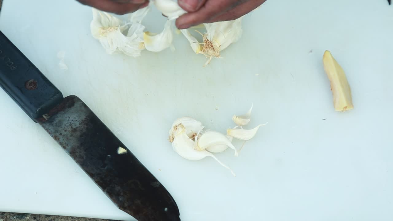 Chopping garlic on a White Chopping board , , traditional outdoor cooking , Chop a piece of ginger
