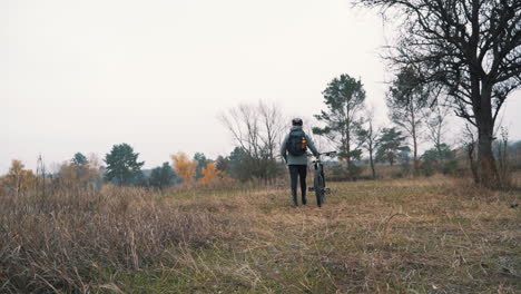 athlete man walking with a mountain bike in the countryside