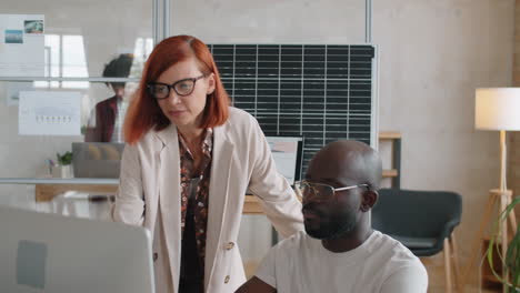 multiethnic man and woman discussing alternative energy project on computer