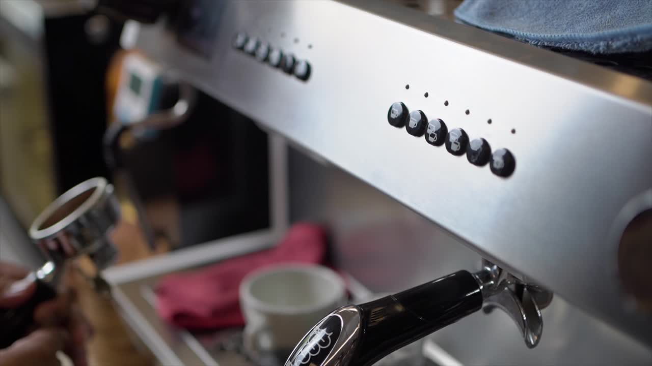 Barista uomo inserisce il portafiltro nella macchina da caffè per preparare un cappuccino o un latte macchiato