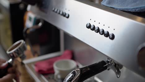 el hombre barista instala un filtro portátil en la máquina de café para hacer capuchino o café con leche