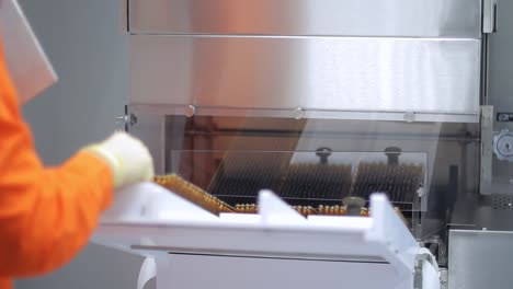 trabajador farmacéutico cargando viales médicos en la máquina de envasado farmacéutico