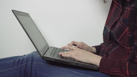foto lateral de una chica escribiendo en una laptop negra - vista lateral, primer plano