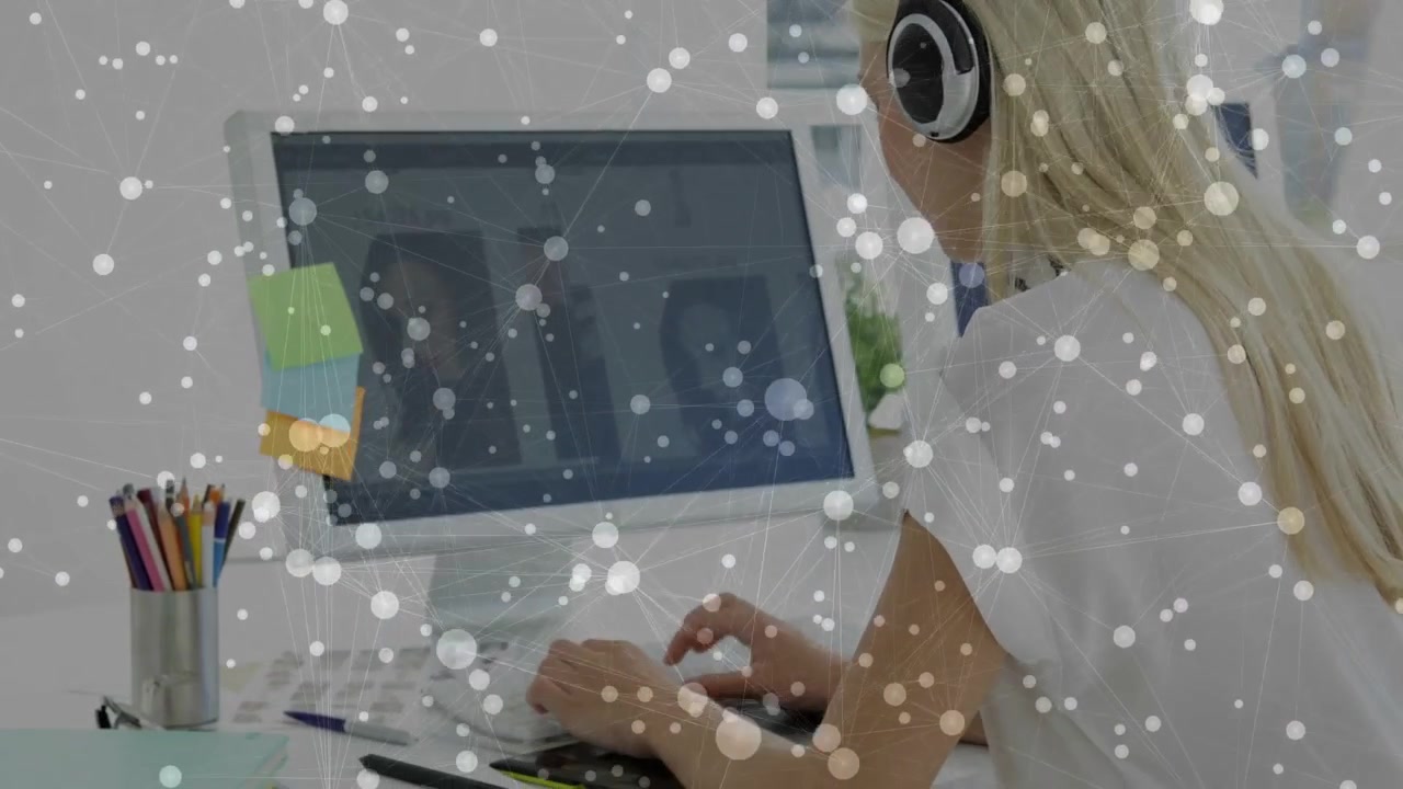Woman leaning forward, typing on keyboard for focused office work, particles drifting over hands