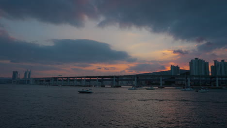 sunset tour yachts travel by gwangan bridge with dramatic sky sunset in busan at blue hour