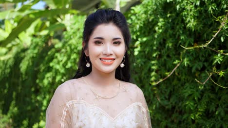 pretty asian woman smiling and walking near green leaves plant wall , slow motion