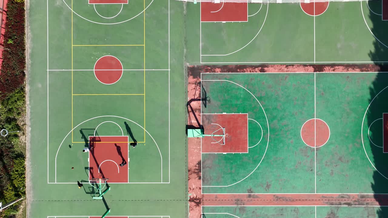 Drone aerial view of people playing basketball together at sunny day
