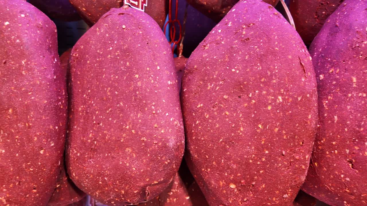 Primo piano di salumi rossi appesi in una salumeria