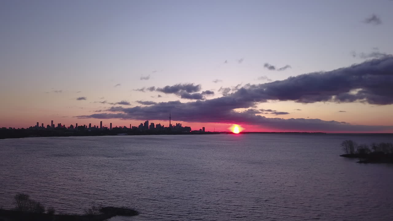 Ilmakuva loistavasta, vaaleanpunaisesta auringonnoususta Ontariojärven ja Toronton horisontin yllä