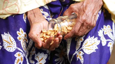 mujer anciana vertiendo cacahuetes de un frasco